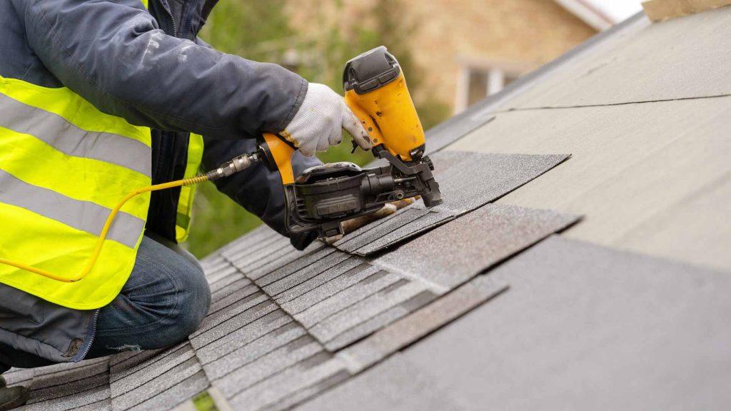 Roofer installing asphalt shingles on roof